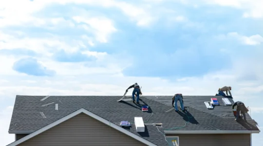 Un couvreur inspecte une membrane de toit plat usée avec des réparations antérieures sur une résidence au Québec.